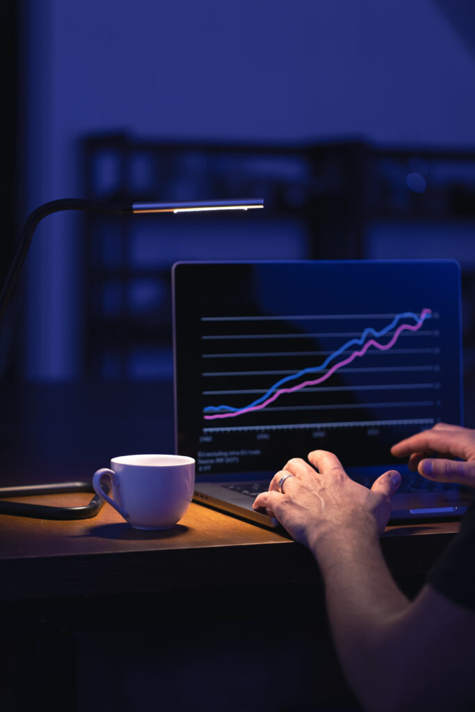 broker looking at laptop analyzing stock market invest trading stocks graph.